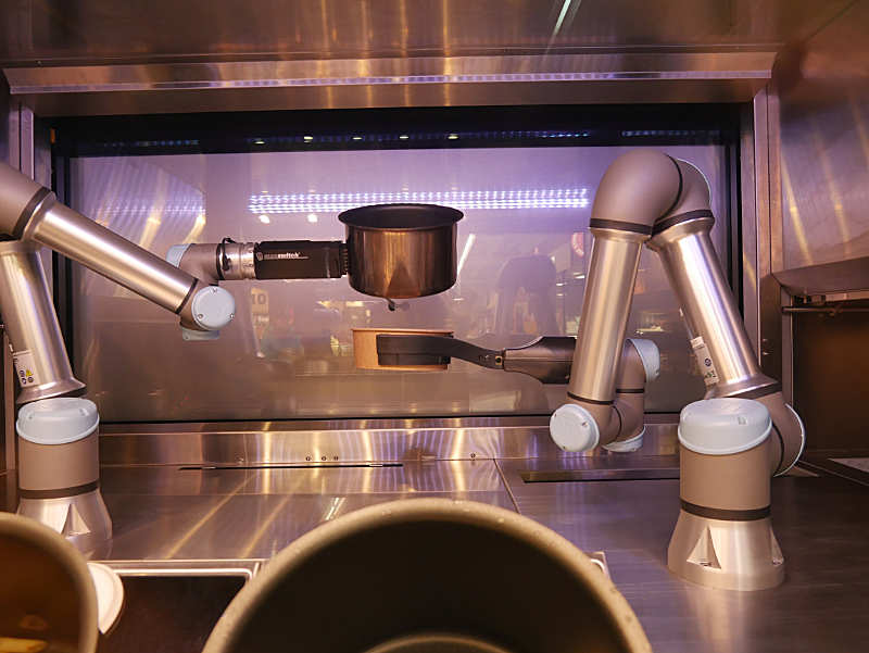 Ein Roboterarm hält den Topf, der andere Roboterarm hält das Transportgefäss