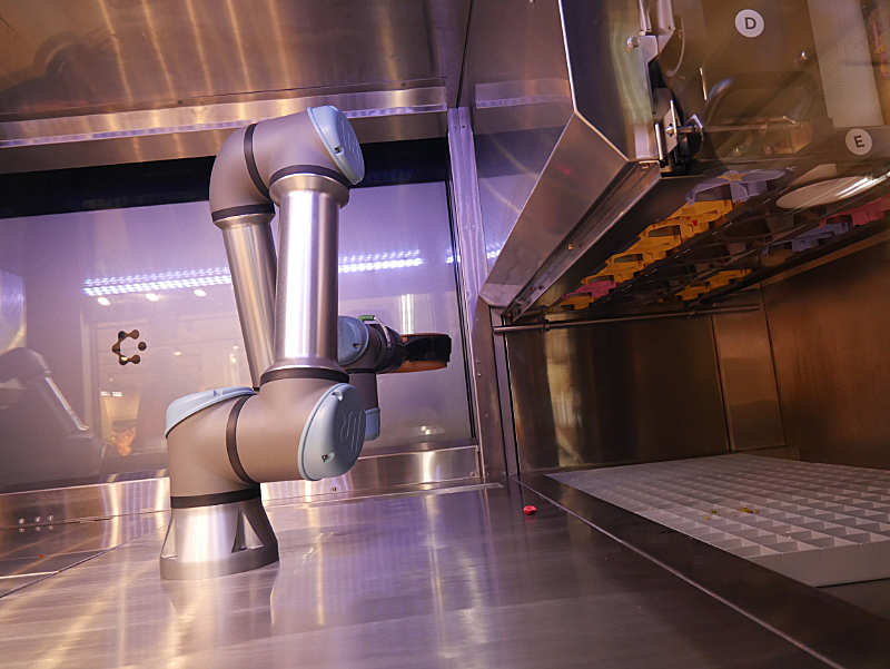 Roboterarm mit Transportbehältnis und Vorratsbehältnis mit weiteren Zutaten