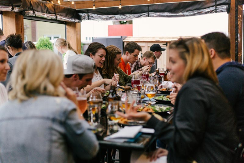 Menschen sitzen an Tischen, essen und reden